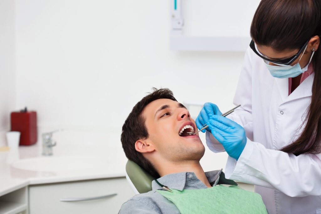 Female dentist examining a male patient at clinic