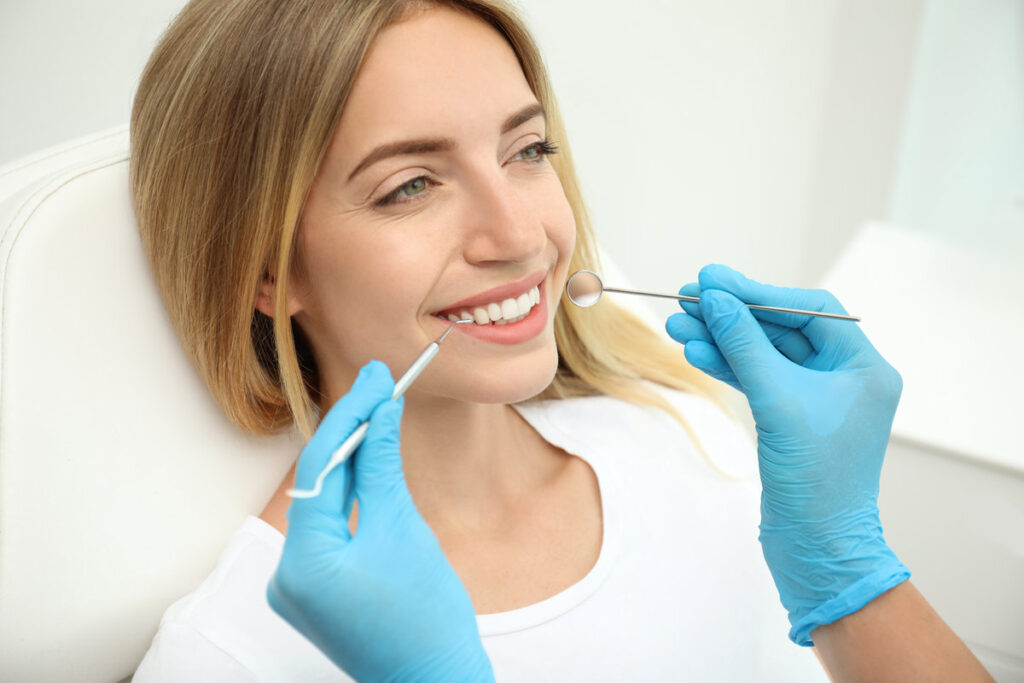 Doctor examining patient's teeth in clinic, closeup. Cosmetic dentistry