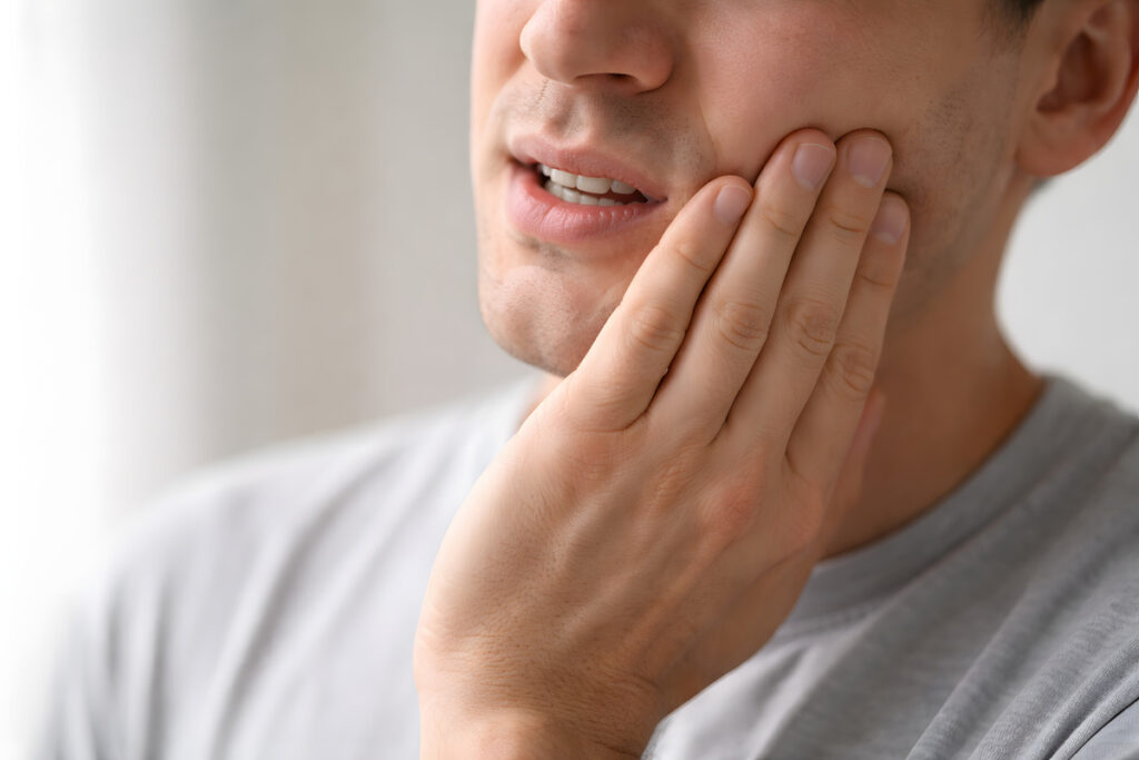 Person Holding Jaw in Pain, Focus on Hand and Lower Face - Dental Pain