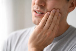 Person Holding Jaw in Pain, Focus on Hand and Lower Face - Dental Pain